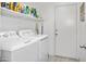 Functional laundry area featuring modern washer and dryer, storage shelves, and convenient access to an exterior door at 907 E Kelsi Ave, San Tan Valley, AZ 85140