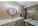 Bathroom boasts a stylish round mirror, modern vanity and a shower-tub combination with glass doors at 9196 E Evans Dr, Scottsdale, AZ 85260