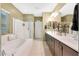 Bright bathroom featuring a soaking tub, walk-in shower, double vanity, and neutral tile flooring at 10746 W Desert Elm Ln, Peoria, AZ 85383