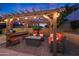 Inviting outdoor living space with a pergola, string lights, and comfortable seating around a fire pit at 10746 W Desert Elm Ln, Peoria, AZ 85383