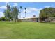 Expansive lawn view of charming home featuring screened-in porch and mature trees at 10839 W Peoria Ave, Sun City, AZ 85351