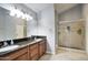 Bathroom with granite counters, a double vanity, framed mirror and a glass-enclosed walk-in shower at 1117 W Manor St, Chandler, AZ 85224