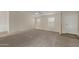 Bright living room with plush carpet, two windows and a modern ceiling fan at 11912 N Thunderbird Rd, Maricopa, AZ 85139