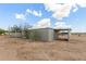 Exterior view of a single-story outbuilding with a covered area, surrounded by arid land and a partly cloudy sky at 11912 N Thunderbird Rd, Maricopa, AZ 85139