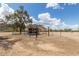 A weathered outbuilding sits in a desert landscape, framed by a partial metal structure and distant mountain views at 11912 N Thunderbird Rd, Maricopa, AZ 85139