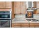 Well-appointed kitchen featuring stainless steel double ovens, a gas cooktop, and plentiful wooden cabinetry at 1344 N Claiborne --, Mesa, AZ 85205