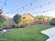 Expansive backyard showcasing manicured landscaping, privacy fencing, lush green grass, and overhead string lights at 1463 E Silver Creek Rd, Gilbert, AZ 85296