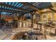 Outdoor kitchen under pergola with stainless steel grill, sink, and dining area at 17728 N 92Nd Pl, Scottsdale, AZ 85255