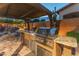 Built-in outdoor kitchen with stainless steel grill, granite countertops, and bar seating at 17728 N 92Nd Pl, Scottsdale, AZ 85255