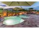 Backyard pool at dusk with lush landscaping, a waterfall feature, umbrellas, and a fire pit at 17728 N 92Nd Pl, Scottsdale, AZ 85255