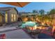 Inviting backyard pool area with a cozy fire pit, lush landscaping, and an umbrella for shade at dusk at 17728 N 92Nd Pl, Scottsdale, AZ 85255