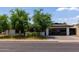 Charming single-story home with lush green trees, a manicured lawn, and a sleek black garage door at 1861 W Navarro Ave, Mesa, AZ 85202