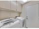 Functional laundry room featuring a washer, dryer, upper cabinets, and access to a door at 20443 N 97Th Ave, Peoria, AZ 85382