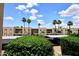 Exterior view of condo complex featuring covered parking, mature palm trees, and beautiful blue sky at 205 N 74Th St # 248, Mesa, AZ 85207