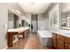 An elegant primary bathroom with double sinks, a separate shower, a soaking tub, and neutral tile at 21353 S 185Th Way, Queen Creek, AZ 85142