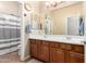 Bright bathroom with dual sinks, wood cabinets, large mirror, and a shower-tub combo at 21353 S 185Th Way, Queen Creek, AZ 85142