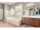 An elegant bathroom featuring a soaking tub, a shower, and a double sink vanity with neutral tile at 21353 S 185Th Way, Queen Creek, AZ 85142