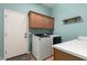 This laundry room features a white washer and dryer, overhead cabinets, and a sink at 21353 S 185Th Way, Queen Creek, AZ 85142