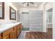 Bathroom with a double vanity, gray tiled walk-in shower, and wood-look flooring at 2270 E Indian Wells Dr, Chandler, AZ 85249