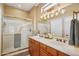 Bright bathroom featuring a double sink vanity, framed mirror, and glass-enclosed shower with gold hardware at 23225 N Hank Raymond Dr, Sun City West, AZ 85375
