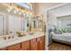 Bright bathroom featuring double sinks and a mirror, with a view into the primary bedroom at 23225 N Hank Raymond Dr, Sun City West, AZ 85375