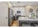 Well-lit kitchen boasts white cabinets, stainless appliances, and island with seating in a neutrally decorated room at 23225 N Hank Raymond Dr, Sun City West, AZ 85375