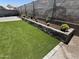 Backyard featuring artificial turf, a retaining wall, and flowers at 2364 N 212Th Ave, Buckeye, AZ 85396