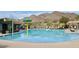 Community pool with water feature, seating and umbrellas with desert landscaping and mountain views at 2364 N 212Th Ave, Buckeye, AZ 85396