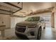 Spacious garage featuring a modern silver SUV, overhead storage racks, and white storage cabinets at 3010 E Cortez St, Phoenix, AZ 85028
