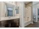 Bright bathroom featuring a dark wood vanity, modern mirror, and a view of the shower/bath area, with neutral wall color at 3422 E Strawberry Dr, Gilbert, AZ 85298