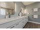 En suite bathroom featuring dual sinks, modern fixtures, decorative mirrors, and storage at 3422 E Strawberry Dr, Gilbert, AZ 85298