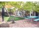 Serene backyard boasts artificial turf, a stone patio, picnic table, trampoline, and mature shade trees, perfect for outdoor fun at 3446 N Ravine --, Mesa, AZ 85215