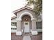 Charming front entrance features a white door with glass panes, framed by an arched entryway with tan pillars and an overhead light fixture at 3446 N Ravine --, Mesa, AZ 85215