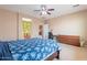 Bright bedroom features a blue floral bedspread, a ceiling fan, a work desk, and a dresser at 3458 E Ivanhoe St, Gilbert, AZ 85295
