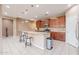 Open-concept kitchen features a breakfast bar island, stainless appliances, wooden cabinetry, and tile floors at 3458 E Ivanhoe St, Gilbert, AZ 85295