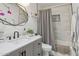 Hall bathroom with gray vanity, white marble walls, shower over tub, and black accents at 4215 E Flower St, Phoenix, AZ 85018