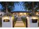 Charming home exterior with a black iron gate, manicured lawn, and illuminated entryway at dusk at 4215 E Flower St, Phoenix, AZ 85018