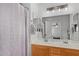Well-lit bathroom features double sinks, wood cabinets, and patterned shower curtain at 4285 E Rousay Dr, San Tan Valley, AZ 85140