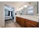 Bright bathroom featuring a long vanity with double sinks, tile floor and a peek into the primary bedroom at 451 S Hawes Rd # 53, Mesa, AZ 85208