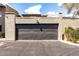 Two car garage with a black door and stucco siding, with an attached front parking area at 618 E Manzanita Pl, Phoenix, AZ 85020