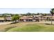Aerial view of a home on a golf course with a mountain backdrop, showcasing lush greenery and blue skies at 6249 E Camelot Dr, Mesa, AZ 85215