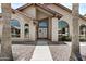 Welcoming front entrance featuring elegant doors, arched windows, and desert landscaping at 6249 E Camelot Dr, Mesa, AZ 85215