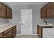 Traditional laundry room offering a utility sink, wood cabinets, and white door and neutral paint at 6249 E Camelot Dr, Mesa, AZ 85215