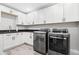 Updated laundry room with modern washer and dryer beneath white cabinets at 6721 N 14Th Pl, Phoenix, AZ 85014