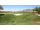 Lush green golf course with sand trap and pond in a scenic desert community at 6917 E Night Glow Cir, Scottsdale, AZ 85266