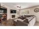 Cozy living room with fireplace, mounted TV, ceiling fan, window shutters, and plush sectional sofa at 9121 E Karen Dr, Scottsdale, AZ 85260