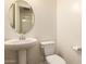 Clean half bath with a pedestal sink and a modern round mirror at 9452 W Parkside Ln, Peoria, AZ 85383