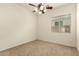 Minimalist bedroom with ceiling fan, carpet flooring, and a window at 9452 W Parkside Ln, Peoria, AZ 85383