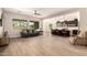 Open-concept living room flows into the kitchen, featuring a large window, wood-look tile, and a ceiling fan at 9452 W Parkside Ln, Peoria, AZ 85383