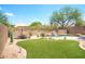 Serene backyard with a custom pool, rock waterfall, grassy area, and mature desert landscaping at 10490 E Morning Star Dr, Scottsdale, AZ 85255